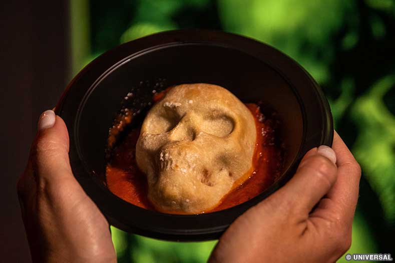 A skull-shaped pepperoni and cheese pizza pocket floating in a pool of marinara sauce