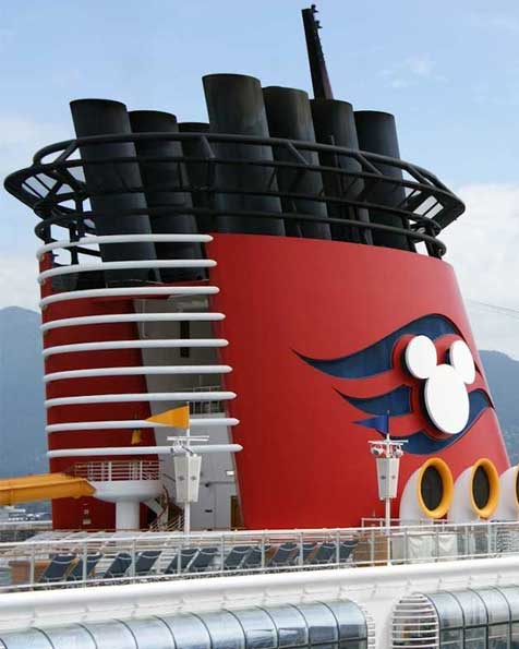 A closeup image of the red funnel smokestack of a Disney Cruise Ship, with a white Mickey Mouse silhouette and blue wave background design