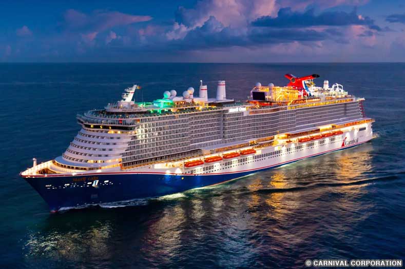 CCL-Carnival-Mardi-Gras A nighttime view of the Carnival Mardi Gras cruise ship, with multicolored lights reflecting on the water