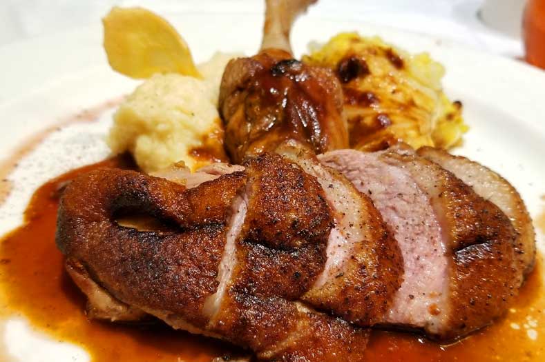 Disney Cruise Food - Roast Duck breast and leg on a plate with a dark sauce