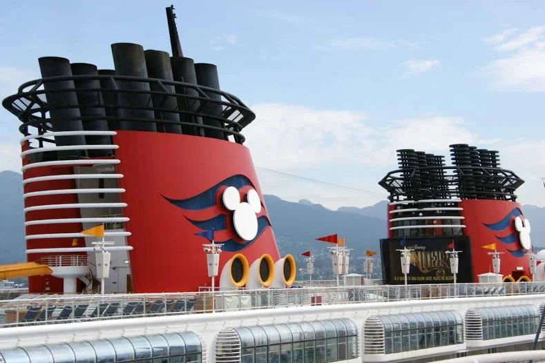 Cruising with Disney for the First Time -- Two red funnels atop a Disney Cruise Ship, each with a Mickey Mouse silhouette in white and a blue wave pattern