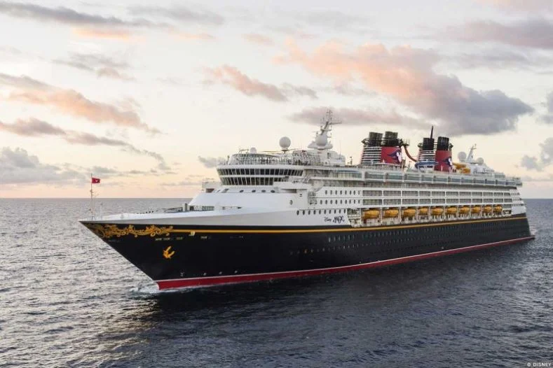 Aerial image of the Disney Magic Cruise Ship sailing with a partly cloudy sky in the background