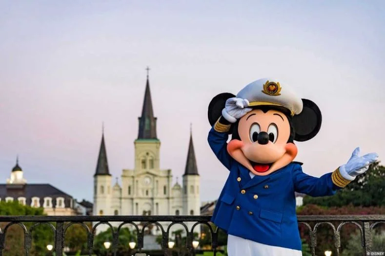 Disney Cruises from New Orleans - Mickey Mouse, in his Disney Cruise costume, poses in front of a wrought iron railing with the iconic St. Louis Cathedral in the background. Image © Disney