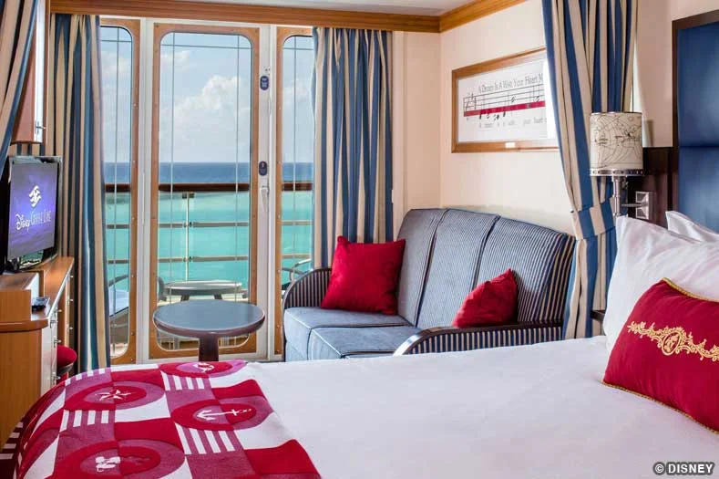 A bed and couch in a Disney Cruise stateroom, leading to an outdoor balcony verandah