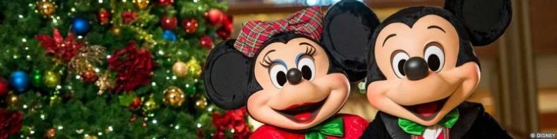 Mickey and Minnie Mouse smiling, in front of a Christmas Tree