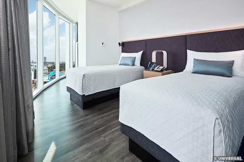 Two twin beds in front of a tall window