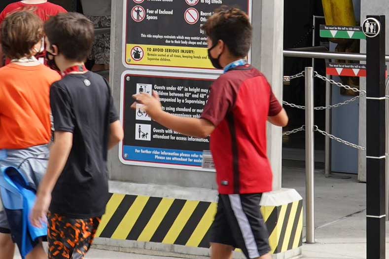 Children walk past a height requirement measuring pylon at Universal Orlando