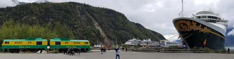 A Disney Cruise Ship in port at Skagway, Alaska, with the White Pass Railway train nearby