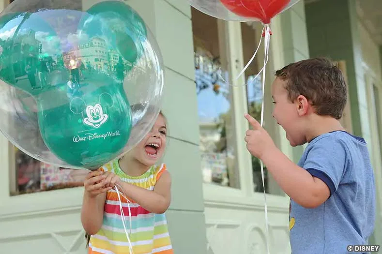 Disney World with Toddlers -- two excited children holding Mickey Mouse balloons | Image © Disney