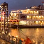An illuminated bridge and a restaurant shaped like a paddlewheel boat at Disney Springs
