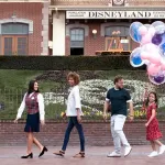 A Disneyland VIP tour guide leads a family in front of the train station