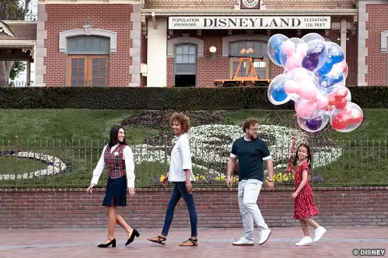 A Disneyland VIP tour guide leads a family in front of the train station