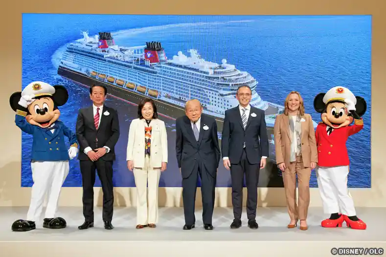 Disney and OLC representatives join Mickey and Minnie Mouse in front of a video screen showing a Disney cruise ship