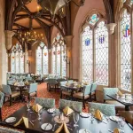 Tables in front of ornate glass windows at Cinderella's Royal Table, among the best Character Dining at Disney World.
