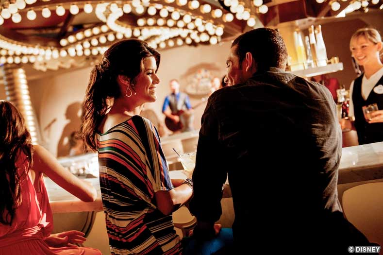 A couple has a drink at a bar themed to a brightly-lit classical carousel