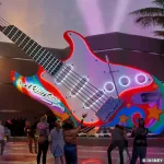 Concept art showing updates to the giant red and white guitar-shaped marquee outside of Rock 'n' Roller Coaster. A psychedelic color scheme has been added. The bridge/neck of the guitar becomes a stylized roller coaster track.