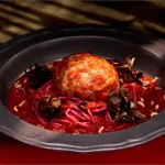 A Vegan Stuffed Cabbage dish with a red sauce, served in a black bowl