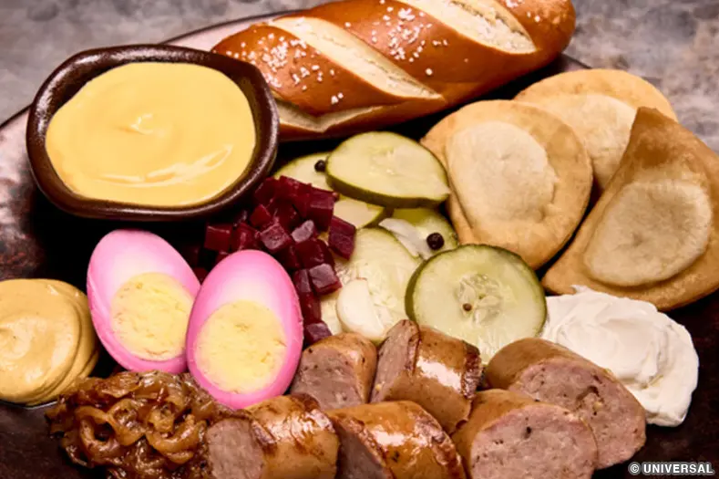 A platter of smoked sausage, potato and cheese pierogies, pickled eggs, marinated beets, caramelized onions, soft pretzel bread, German mustard, and cheese fondue