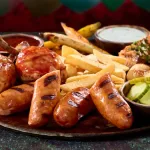 Where to eat at epic universe - a thawfest platter with chicken, salmon, sausage, carrots, onions, fries, and sauces