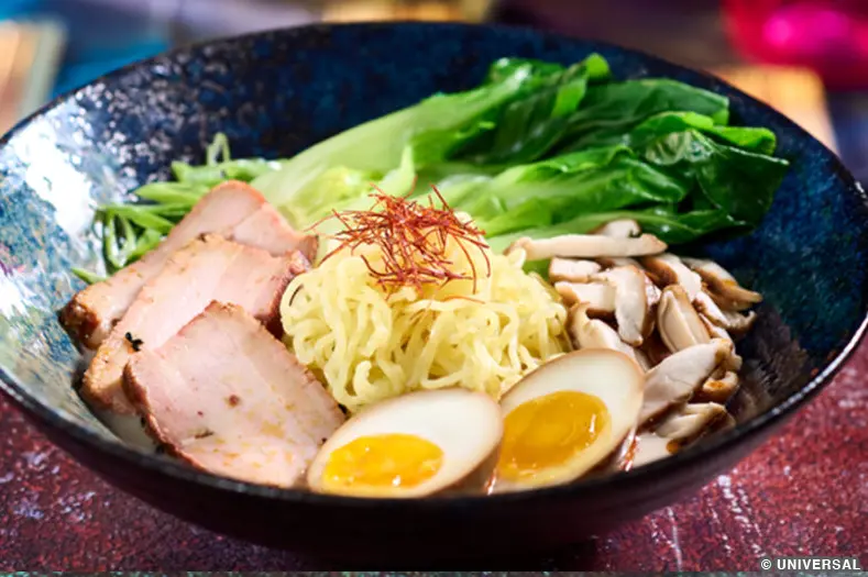A bowl of ramen and pork broth, topped with pork, egg, shiitake mushrooms, and togarashi oil